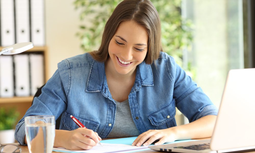 Woman writing on paper as she agrees to a 24 hour payday loan