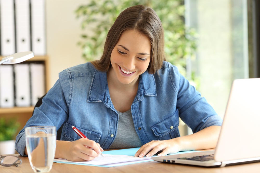 Woman writing on paper as she agrees to a 24 hour payday loan